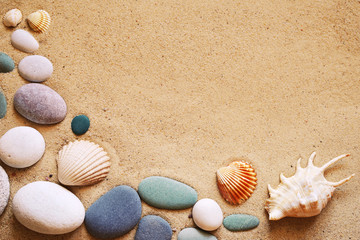Fototapeta na wymiar Seashells and stones on sand. Sea summer vacation background with space for the text