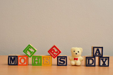 Mothers day spelled with colorful alphabet blocks and a white teddy bear