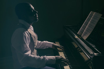 Afro American man playing piano in darkness