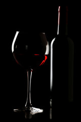 Glass of wine with bottle in darkness