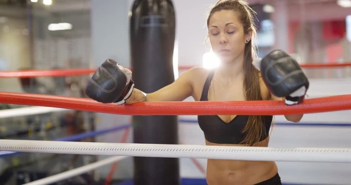Real and powerful woman rests after workout in boxing ring