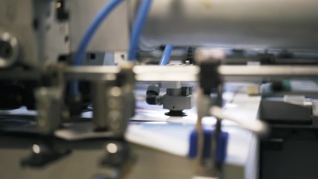 Close up of a printing plant machine insides with wires and gears during its work process. Left to right pan real time close up shot