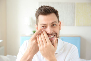 Young man putting contact lenses at home