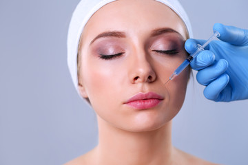 Cosmetic injection on the pretty woman face. Isolated on gray background