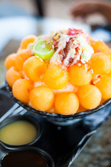 bingsu is a Korean shaved ice dessert with sweet toppings such as chopped fruit, condensed milk, fruit syrup, and red beans.
