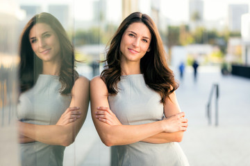 Beautiful attractive woman casual standing next to shiny reflective building during travel for business