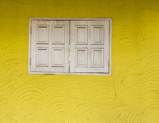 Architecture detail, yellow cement wall texture and old white wooden window