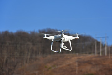 A drone with a camera flying over land.  Drones are a popular tool used for aerial photography. 