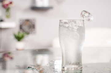 Glass of water and ice on table