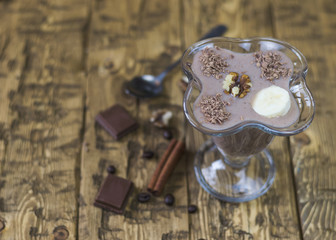 Chocolate banana smoothie with nuts on a wooden table. The concept of a vegetarian diet.