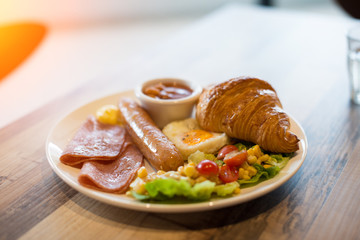 English breakfast with fried eggs, bacon, sausages, beans, toasts and fresh salad