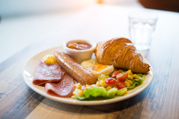 English breakfast with fried eggs, bacon, sausages, beans, toasts and fresh salad