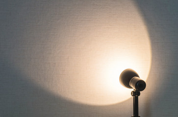 Closeup wallpaper wall textured background with blurred small lamp with brown light shine to the wall with copy space