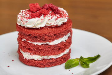 Round red velvet cake with cream on white plate