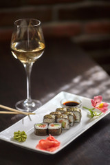 Sushi rolls on white plate and glass of wine