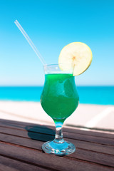 Green cocktail with apple piece on wooden table