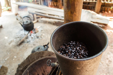 Fototapeta premium old vintage manual coffee mill or grinder with coffee been and old vintage kettle in background with the scene of the shade of the housing of the hill tribes, soft focus, selective focus.