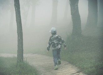 Little boy running through the fog in forest : Soft focus