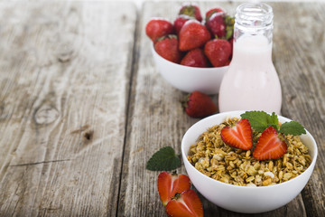 Granola with strawberry on a wooden table.