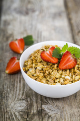 Granola with strawberry on a wooden table.