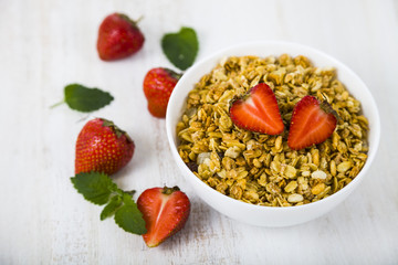 Granola with strawberry on a wooden table.