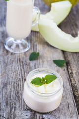 Yogurt and smoothie with melon on a wooden table.
