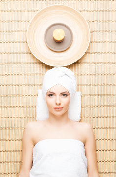 Beautiful, young and healthy woman in spa salon on bamboo mat. Spa, health and healing concept.