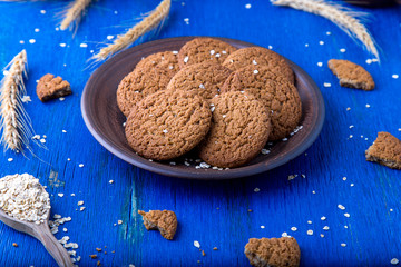 Oatmeal cookies in brown plate on blue background. Rustic style. Close up