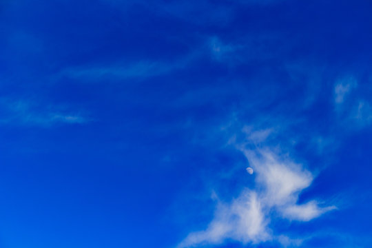 Half moon amidst wispy clouds - Powered by Adobe