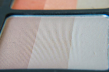 Close-up of pressed, pearl eye shadows, beige arc in a magnetic stand.