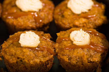 Delicious brown colored muffins lined up with caramel and cream topping, as seen from above angle, pastry concept