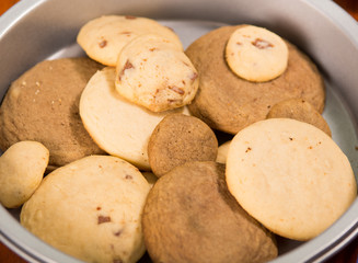 Selection of different sized brown colored cookies, lying in a bowl as seen from above, pastry concept