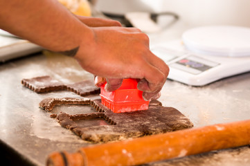 Bakery man cutting delicious christmas chocolate cookies in a bakery store