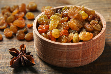 Raisins in a wooden bowl on a wooden background