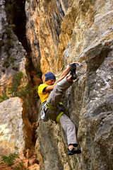 Young male climber hanging on a cliff with a rope. 
