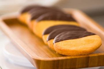 Closeup of a delicious fresh vanilla cookie with chocolate on wooden desk