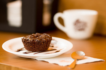 Delicious chocolate cake in plate on rustic wooden table with a spoon over a napkin