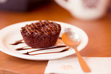 Delicious chocolate cake in plate on rustic wooden table with a spoon in plate