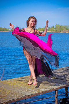A beautiful girl from a harem in an oriental Arabic costume for belly dancing on the nature around lake walks and enjoys a sunny afternoon on the territory