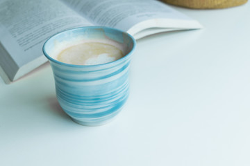 Blue coffee cup on the desk with books. Concept coffee lover background.