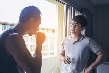 Asian man talking with friend while holding water bottle, lifestyle people concept.