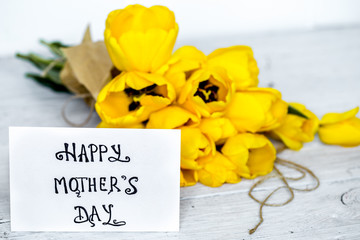 postcard Mother's Day and yellow tulips on wooden background