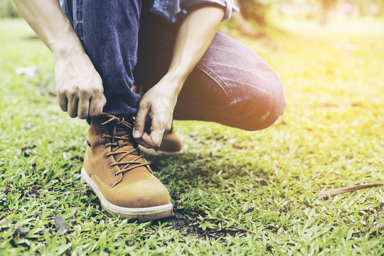 Young man binding shoes on thr grass, Vintage style photo.