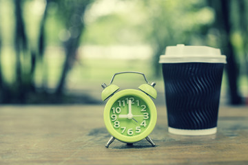 Naklejka premium Retro clock and coffee cut on wood table, vintage color tone.