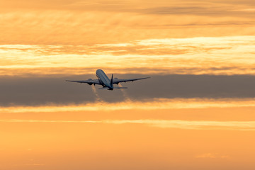 Fototapeta na wymiar Flugzeug fliegt in den Sonnenuntergang 