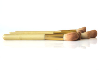 A close-up set of professional make-up brushes with a reflection on a white table. The set includes brushes for: backgrounds, camouflage, powder, blush and 3 shade applicators.