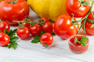 Composition of large tomatoes, cherry, pumpkin, and a glass of juice on a paternal background.
