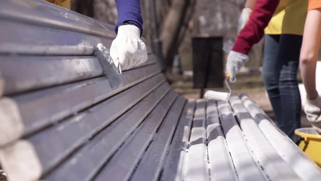 female hands in gloves paint a bench