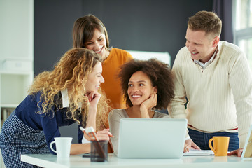 Young people working in modern office, discussing in front of laptop
