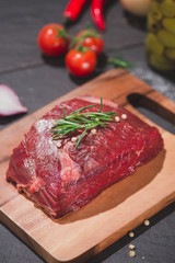 Raw beef on a cutting board  with spices and ingredients for cooking.